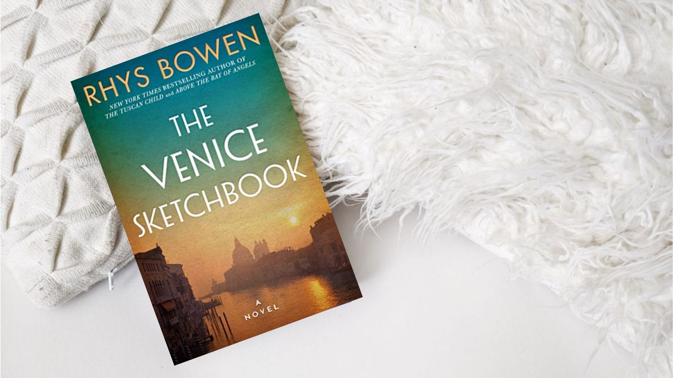 The Venice Sketchbook book against white pillows and background