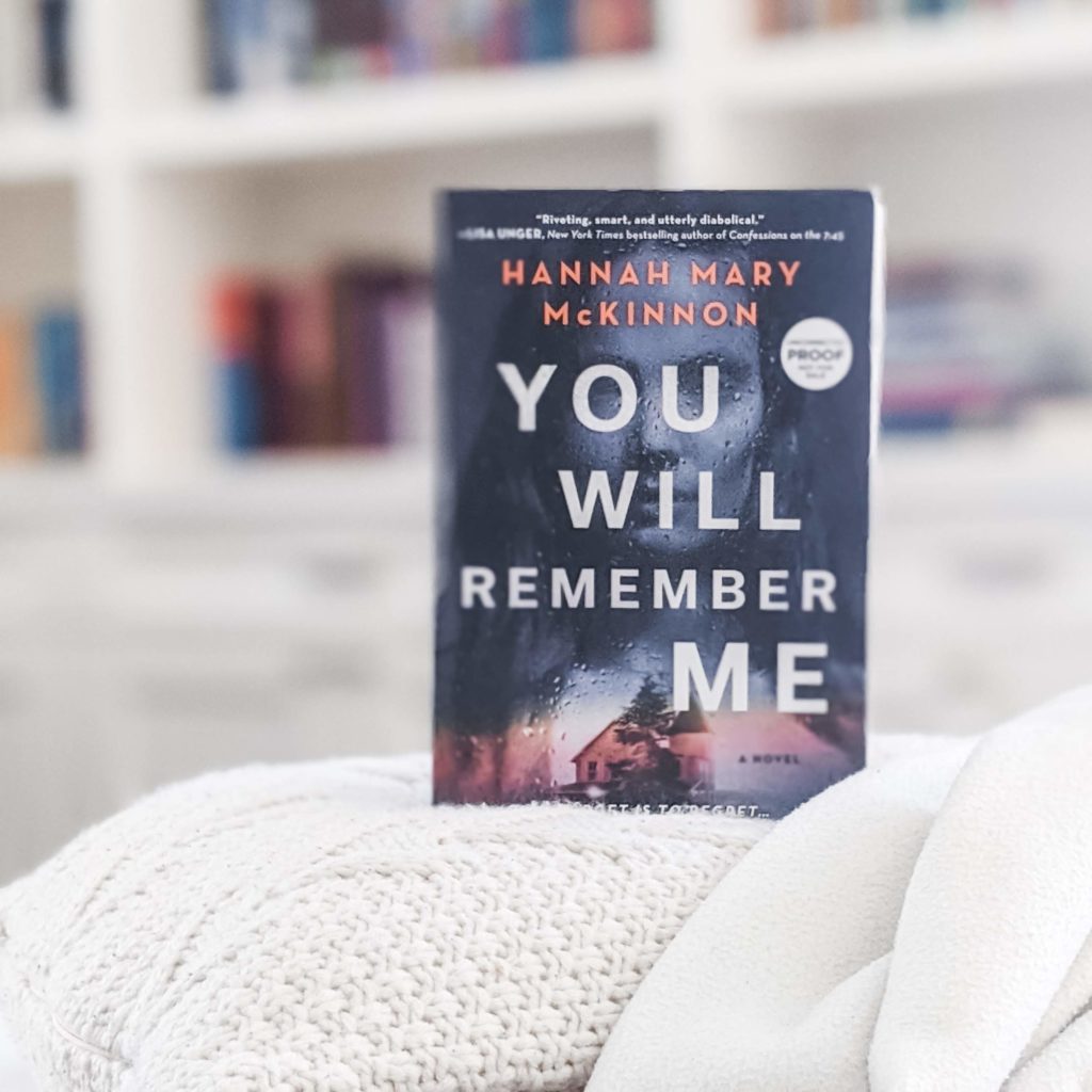 You Will Remember Me book by Hannah Mary McKinnon, set on top of a white pillow and blanket
