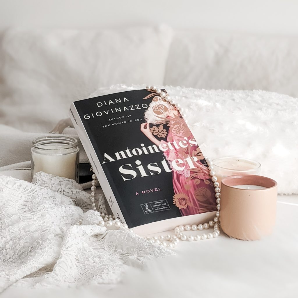 Antoinette's Sister book set against white background with candles. Photo by The 52 Book Club